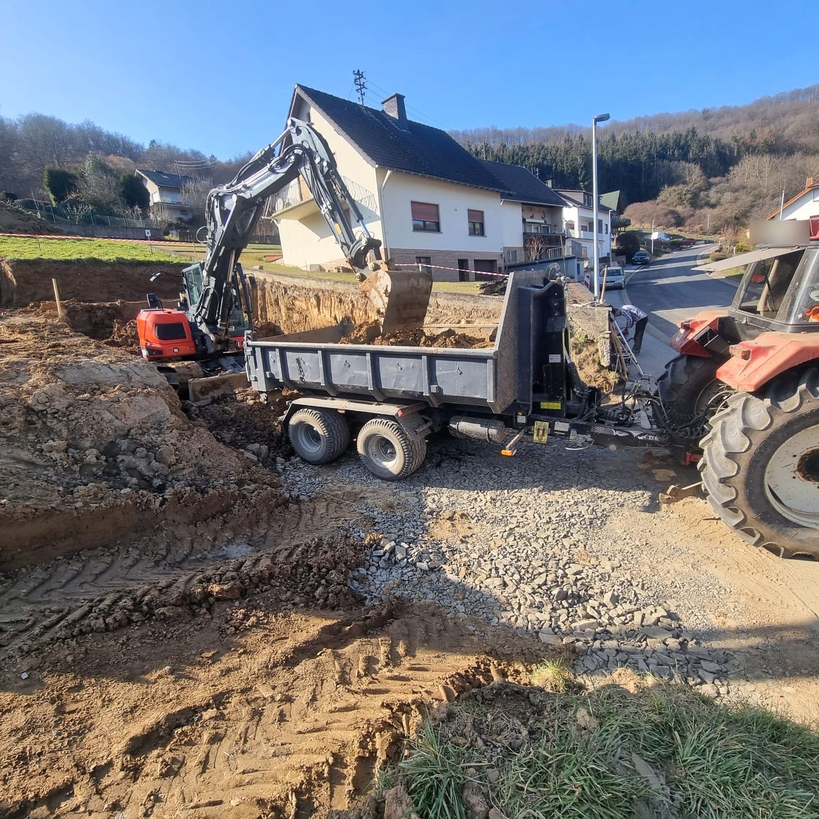 Bagger lädt Aushub aus einer Baugrube auf einen Kippanhänger
