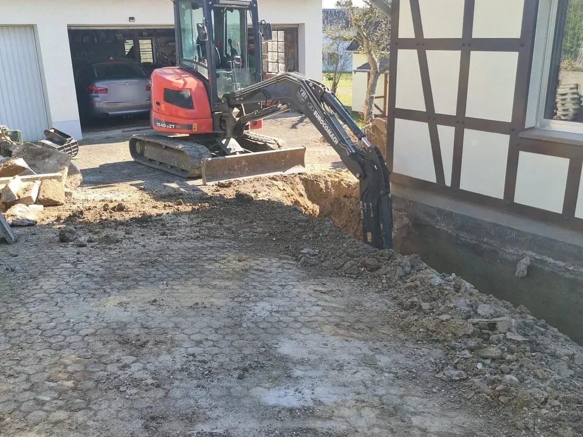 Minibagger legt das Mauerwerk eines Fachwerkhauses frei
